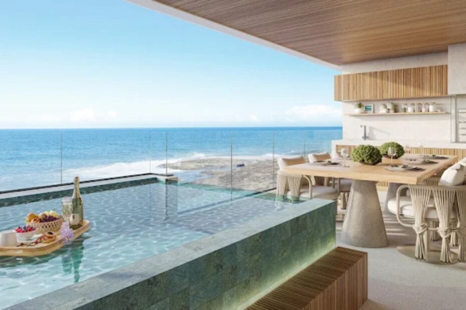 Fachada moderna do Manami Ocean Living Guarapari com piscinas nas varandas e vista panorâmica para o mar da Enseada Azul.