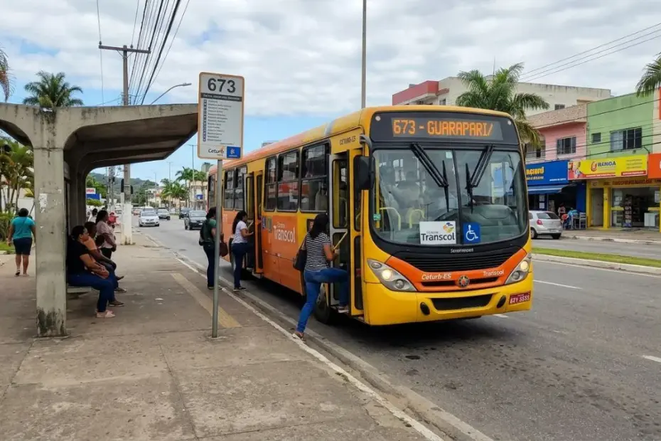 Ônibus amarelo do Transcol da linha 673 com letreiro "673 - GUARAPARI" parado em um ponto de ônibus no bairro Muquiçaba.