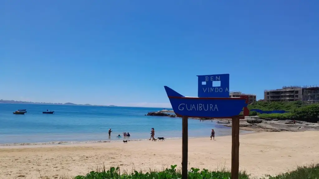 Vista panorâmica da Praia de Guaibura em Guarapari com mar calmo e barcos de pesca na areia.