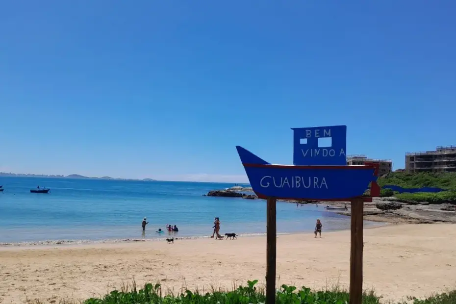 Vista panorâmica da Praia de Guaibura em Guarapari com mar calmo e barcos de pesca na areia.