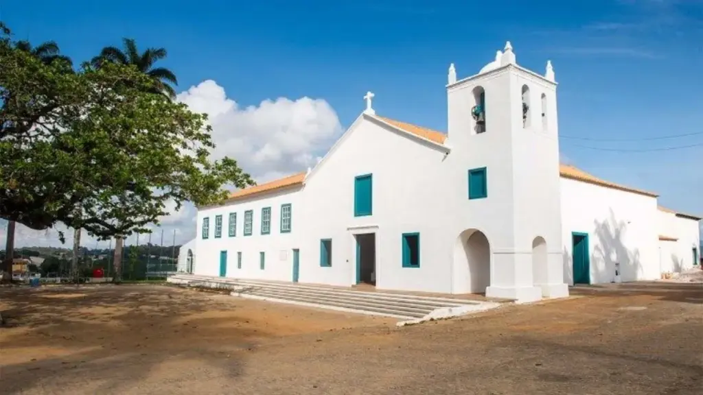 Fachada branca do Santuário Nacional de São José de Anchieta em Anchieta, Espírito Santo, com janelas e portas azuis e torre sineira sob céu azul.