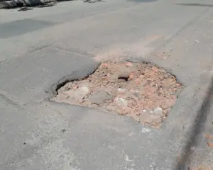 Registro da Crise na Infraestrutura viária na Enseada Azul em Guarapari, com asfalto apresentando buracos profundos.