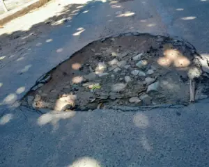 Registro da Crise na Infraestrutura viária na Enseada Azul em Guarapari, com asfalto apresentando buracos profundos.