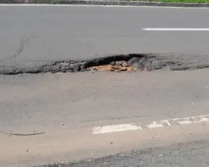 Registro da Crise na Infraestrutura viária na Enseada Azul em Guarapari, com asfalto apresentando buracos profundos.