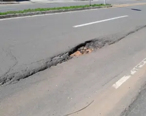 Registro da Crise na Infraestrutura viária na Enseada Azul em Guarapari, com asfalto apresentando buracos profundos.