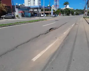 Registro da Crise na Infraestrutura viária na Enseada Azul em Guarapari, com asfalto apresentando buracos profundos.