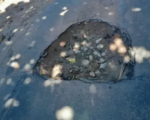 Registro da Crise na Infraestrutura viária na Enseada Azul em Guarapari, com asfalto apresentando buracos profundos.