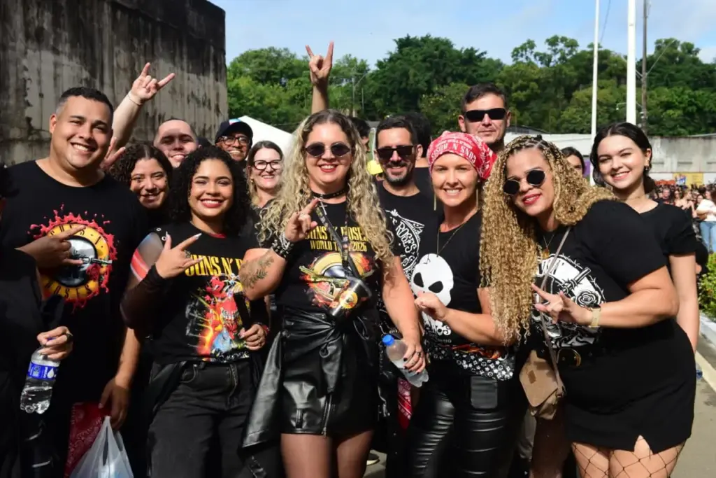 Fãs sorridentes com camisetas da banda no show do Guns N' Roses no Kleber Andrade, otimizado por Especialista Raimundo Oliveira SEO RedeVix.