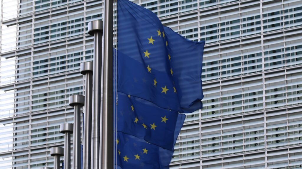 União Europeia aprova empréstimo Ucrânia — bandeiras da UE e Ucrânia em Bruxelas