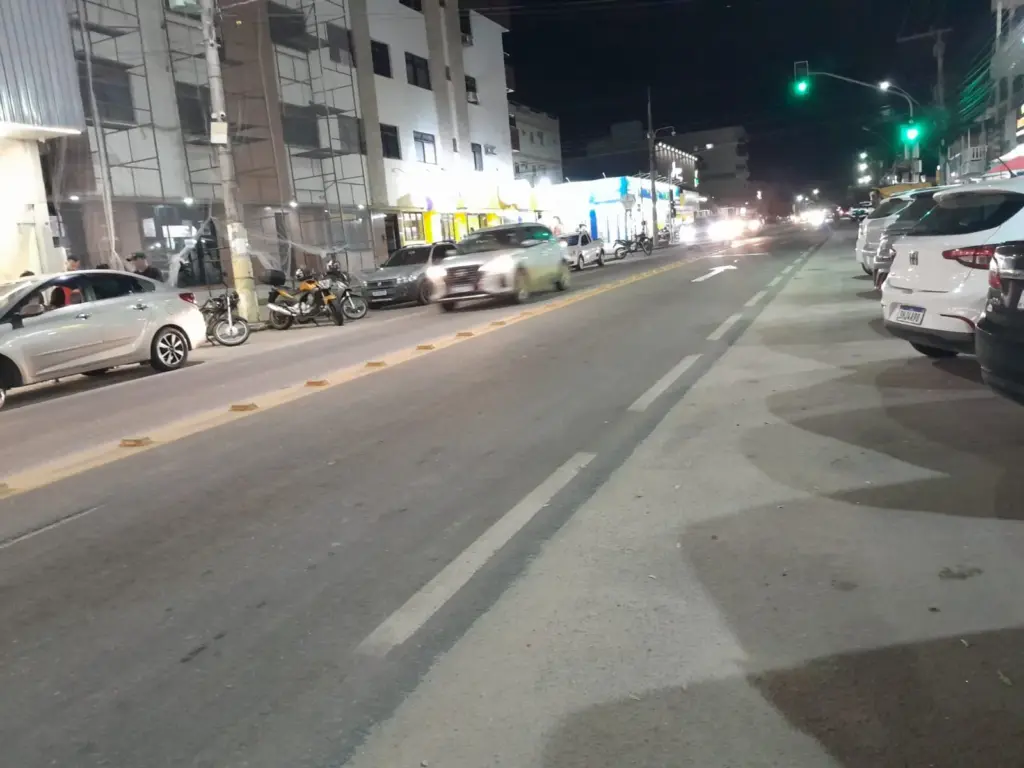 Rua principal de Meaípe à noite com trânsito fluido e sinalização verde em Guarapari.