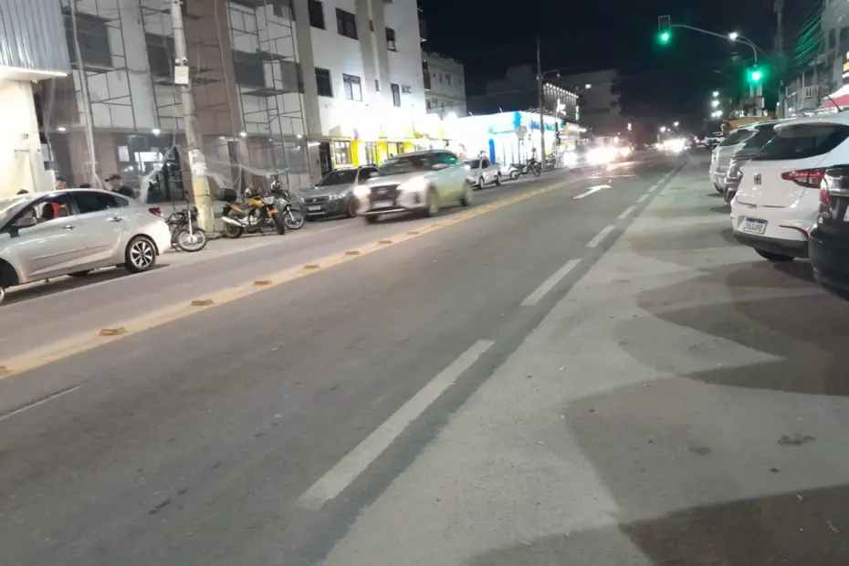 Rua principal de Meaípe à noite com trânsito fluido e sinalização verde em Guarapari.