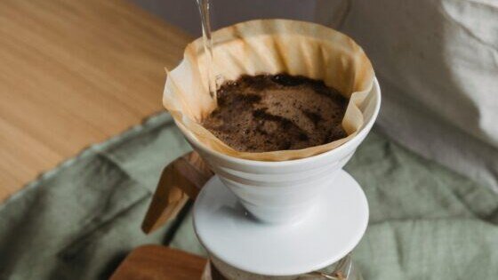 Imagem de especialistas em café discutindo dicas para preparar a bebida perfeita em casa, com grãos e utensílios.