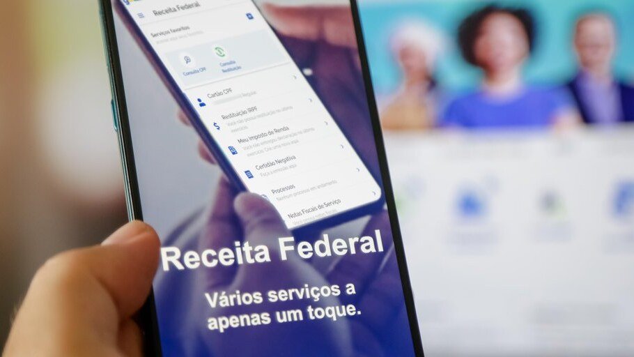 Imagem de um contribuinte consultando a lista de restituição do Imposto de Renda 2026 no celular ou computador.