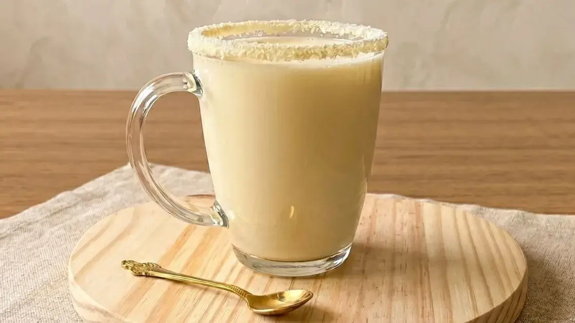 Leite Ninho quente cremoso servido em um copo transparente, com espuma e um toque de canela por cima.