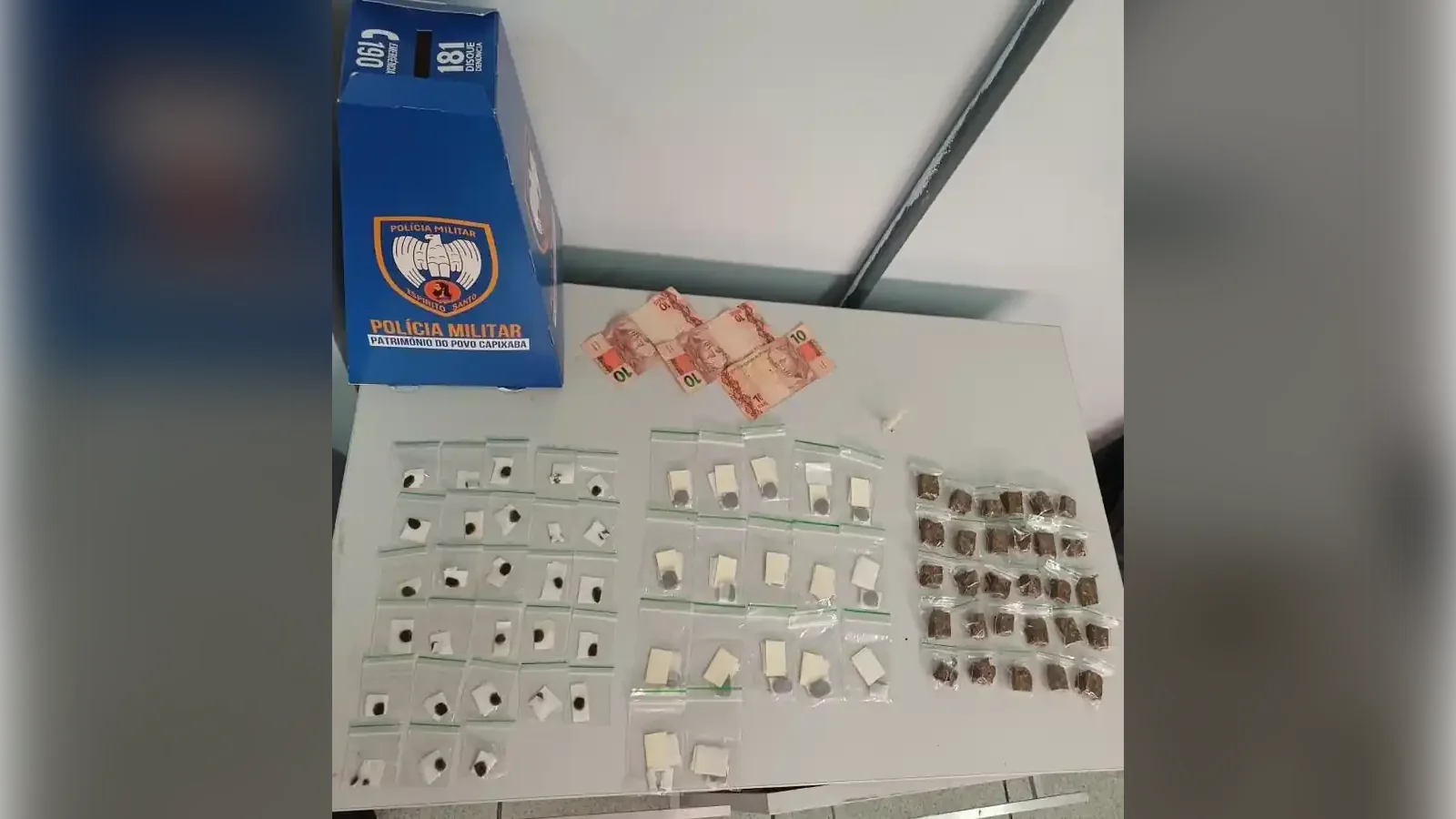 Drogas, R$ 30 e caixa da Polícia Militar sobre mesa após apreensão no bairro Santo André, em Vitória
